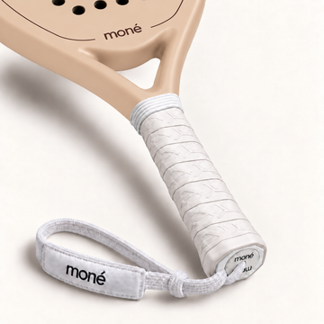 White textured grip, logo end cap and moné wrist strap on the Sahara beige padel racket, close-up