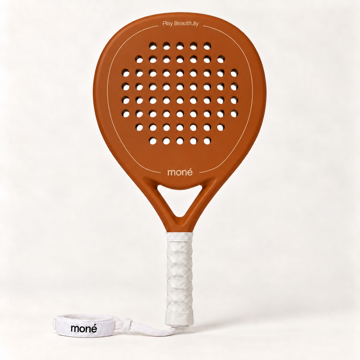 Sienna light brown padel racket by moné, front view: teardrop head, Play Beautifully lettering, white grip and wrist strap