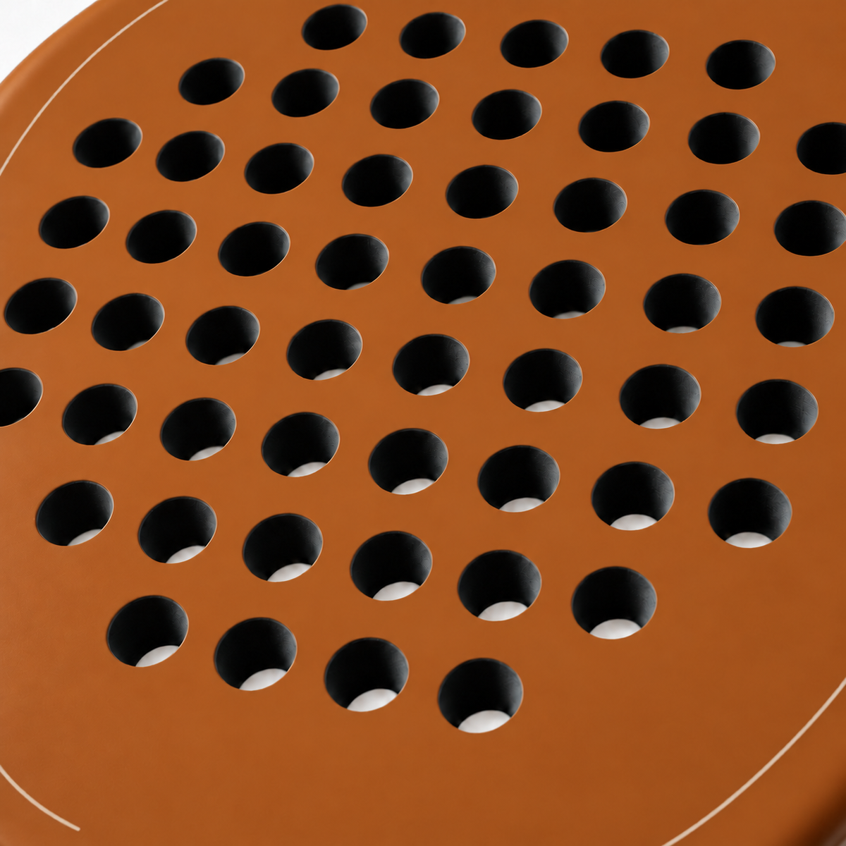 Macro of the Sienna light brown padel racket face, showing its matte finish, drilled hole pattern and thin cream outline