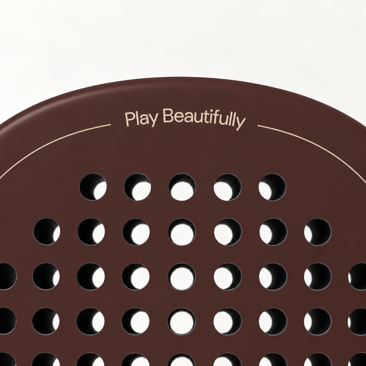 Play Beautifully printed in beige at the top of the Cocoa brown padel racket, above its drilled hole pattern