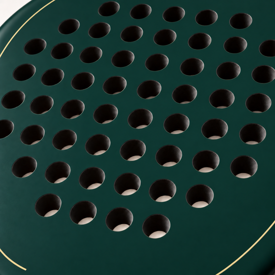 Macro of the Forest dark green padel racket face, showing its matte finish, drilled hole pattern and thin gold outline