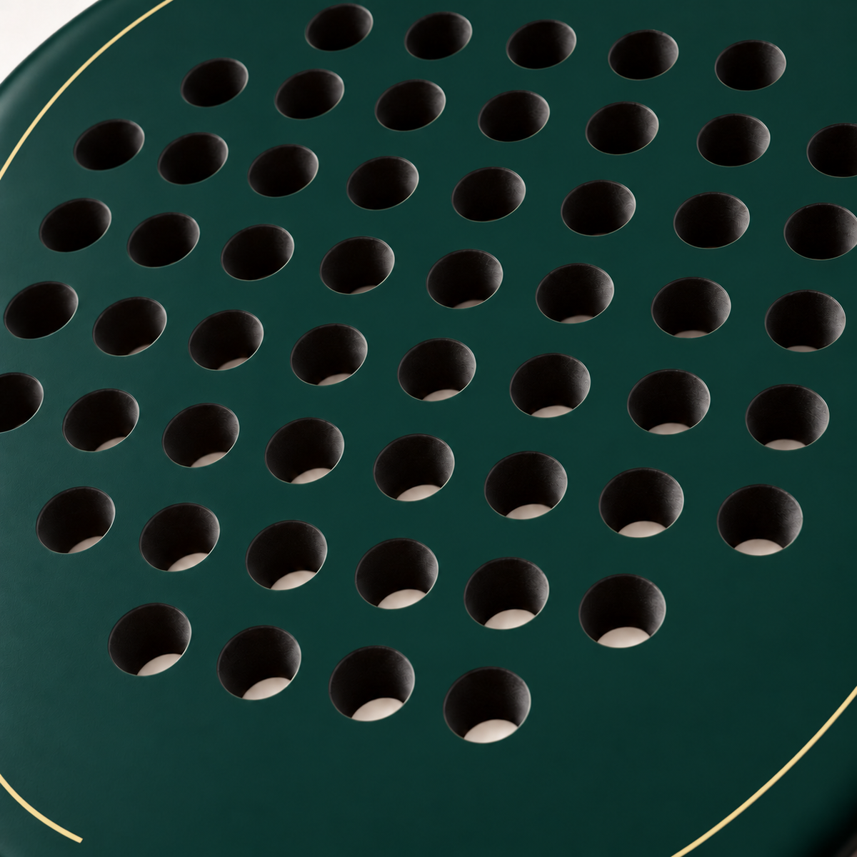 Macro of the Forest dark green padel racket face, showing its matte finish, drilled hole pattern and thin gold outline