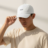 Person wearing a white cap with 'moné' branding against a neutral background. Classic Cotton Cap - White | Moné Padel