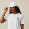 Person wearing a white t-shirt and cap with branding on a beige background. Classic Cotton Cap - White | Moné Padel
