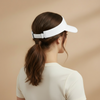 Person wearing a white visor against a beige background. Court Visor - White | Moné Padel