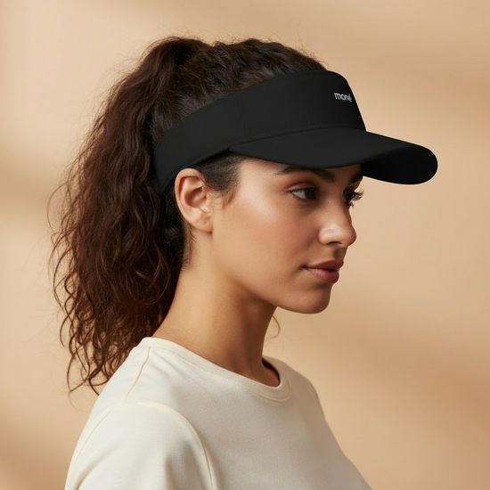 Woman wearing a black visor against a beige background. Court Visor - Black | Moné Padel