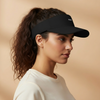 Woman wearing a black visor against a beige background. Court Visor - Black | Moné Padel