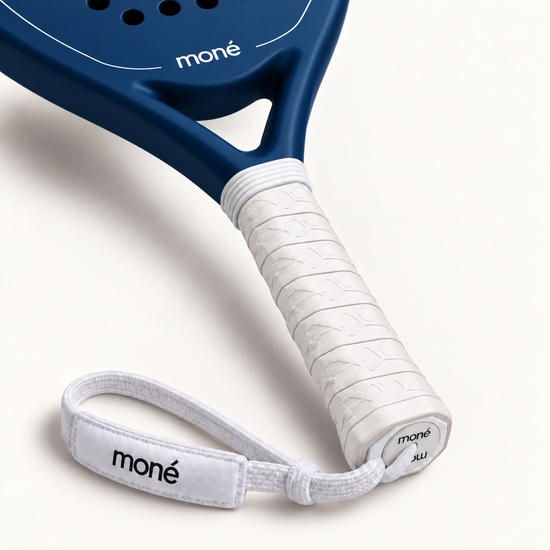 White textured grip, logo end cap and moné wrist strap on the Sailor blue padel racket, close-up