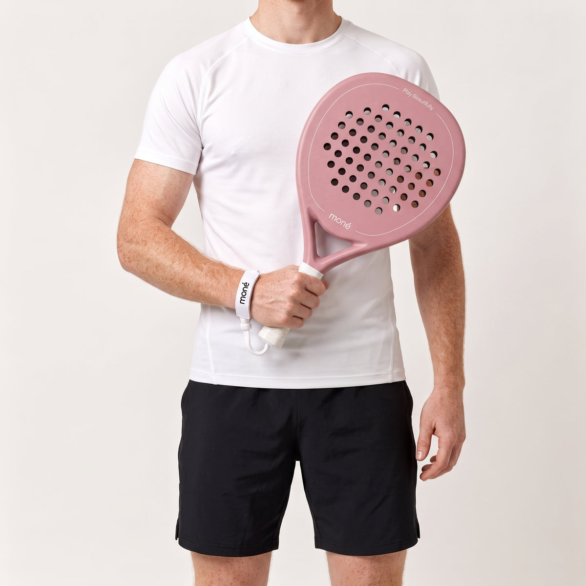 Man in a white T-shirt and black shorts holding the pink Himalaya Hybrid padel racket in front of his chest