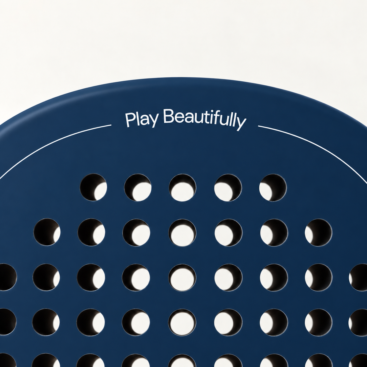 Play Beautifully printed in white at the top of the Sailor blue padel racket, above its drilled hole pattern