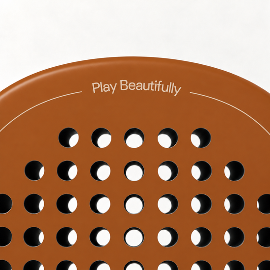 Play Beautifully printed in cream at the top of the Sienna light brown padel racket, above its drilled hole pattern