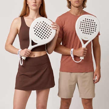 Woman in brown and man in a terracotta tee each hold the off-white Ivory Hybrid padel racket by moné