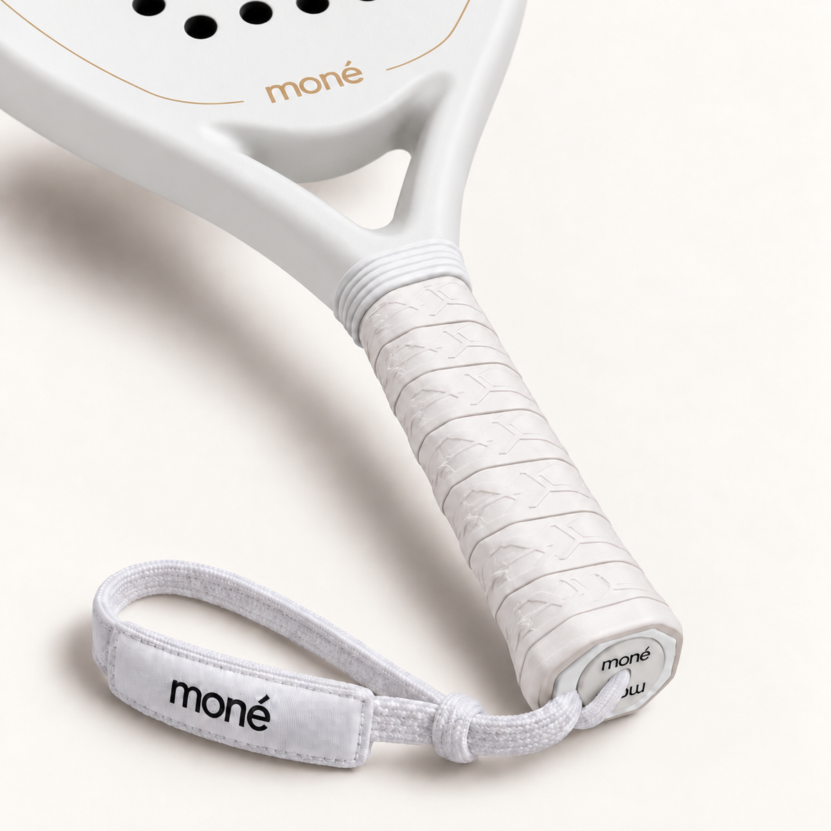 Textured white grip, logo end cap and wrist strap shown up close on the off-white Ivory Hybrid padel racket