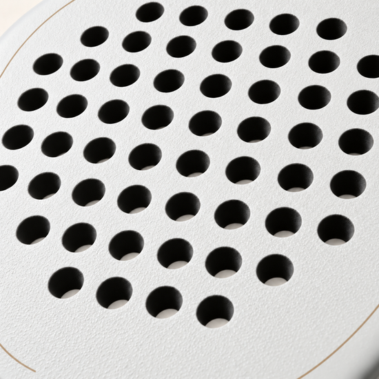 Macro of the off-white Ivory Hybrid padel racket face, showing its rough spin texture and drilled hole pattern