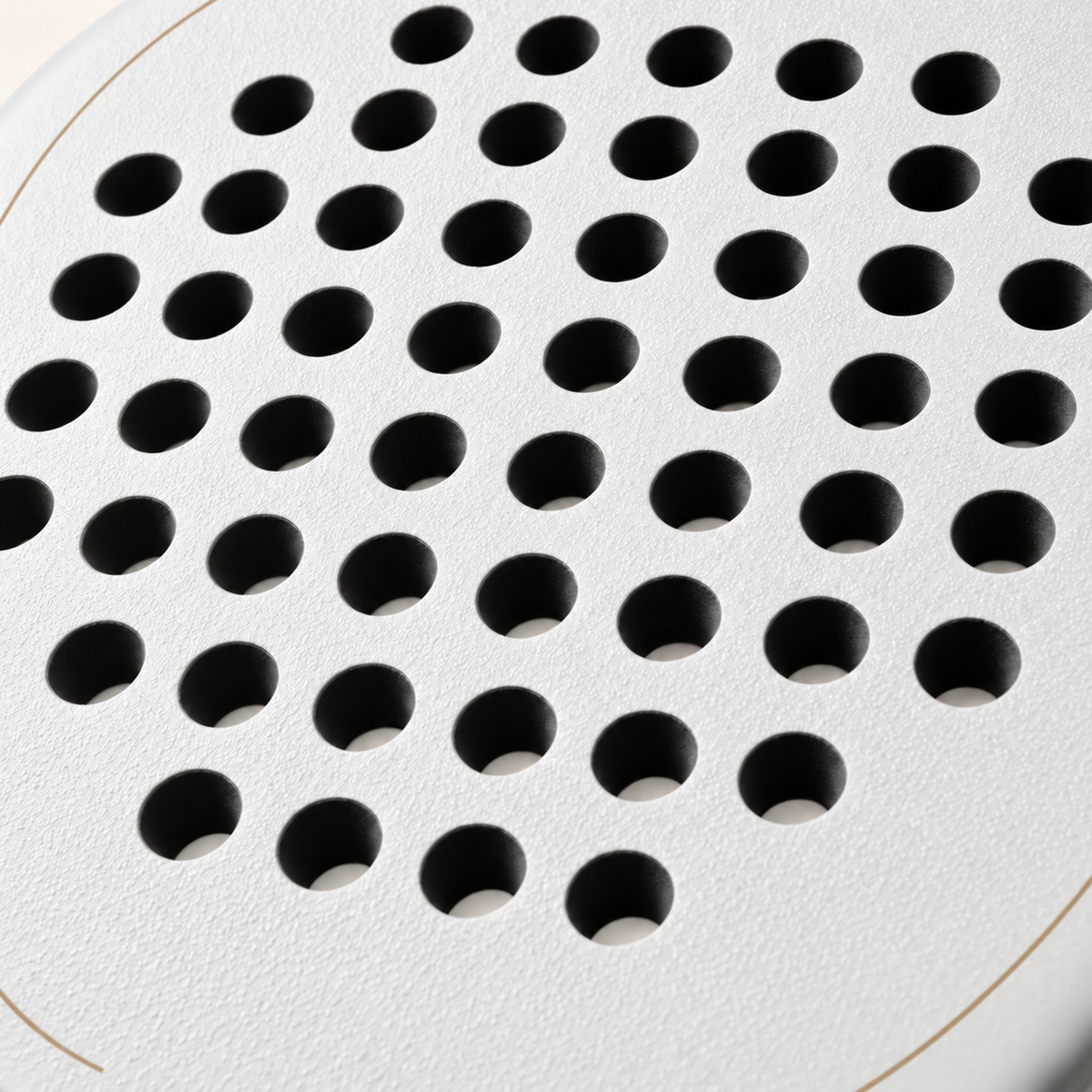 Macro of the off-white Ivory Hybrid padel racket face, showing its rough spin texture and drilled hole pattern