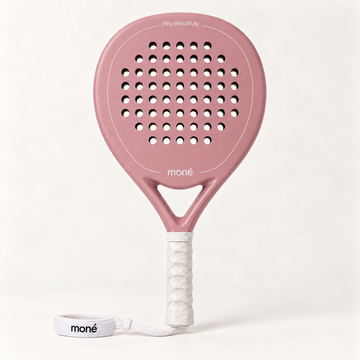 Front view of the pink Himalaya Hybrid padel racket by moné, with a white grip and wrist strap on a cream backdrop
