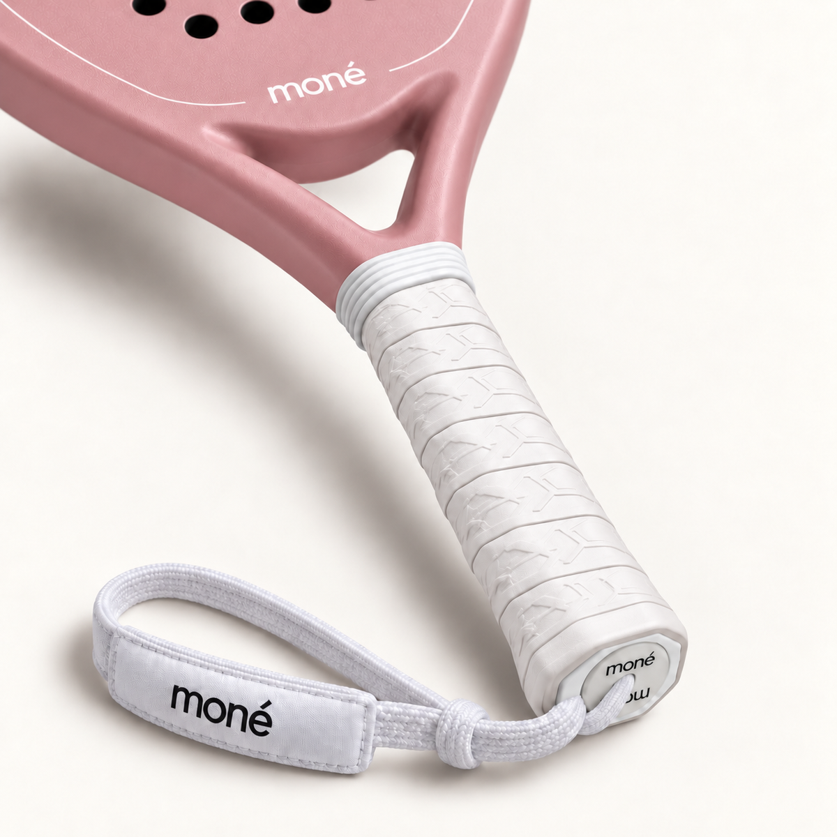 Close-up of the white textured grip, logo end cap and wrist strap on the pink Himalaya Hybrid padel racket