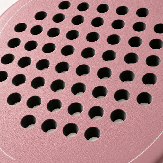Macro of the rough textured face and drilled hole pattern on the pink Himalaya Hybrid padel racket