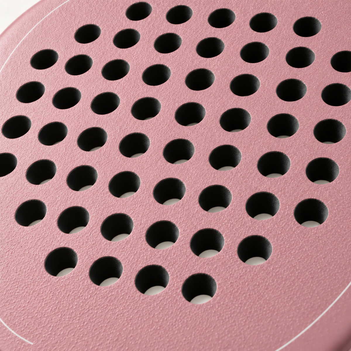 Macro of the rough textured face and drilled hole pattern on the pink Himalaya Hybrid padel racket