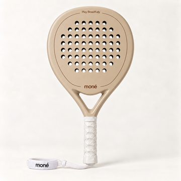 Sahara Hybrid padel racket by moné in beige, front view with a white grip and wrist strap on a light backdrop