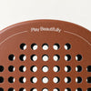 Play Beautifully printed in cream at the top of the light brown Sienna Hybrid padel racket, above its hole pattern